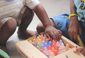 Foto: Kinder hocken vor einer Kiste voller Kreide